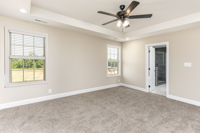 carpeted empty room featuring a tray ceiling and ceiling fan