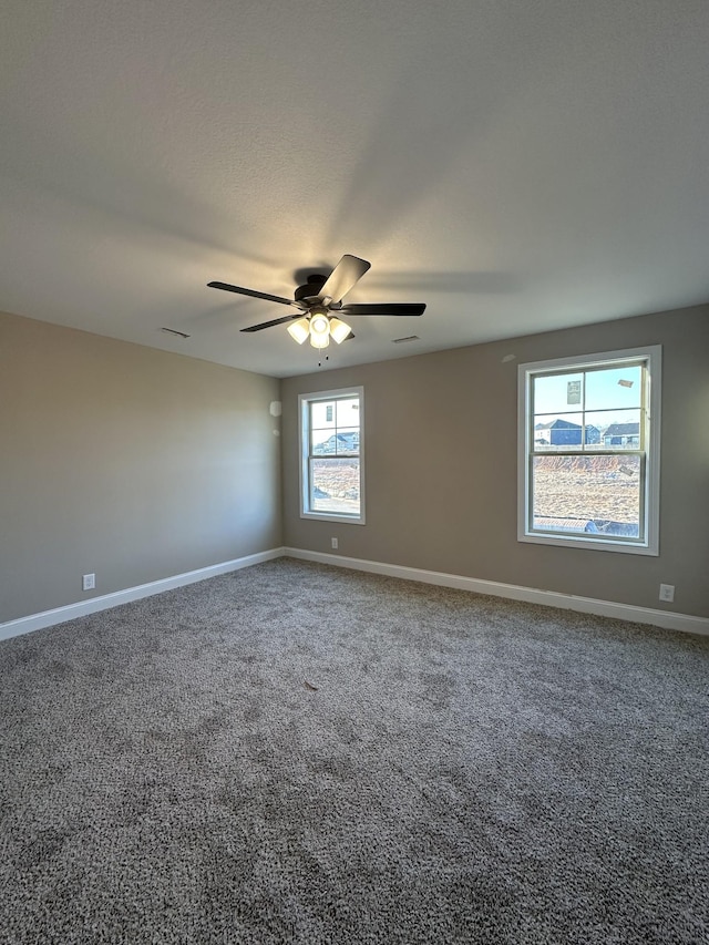 spare room with a ceiling fan, visible vents, baseboards, and carpet floors