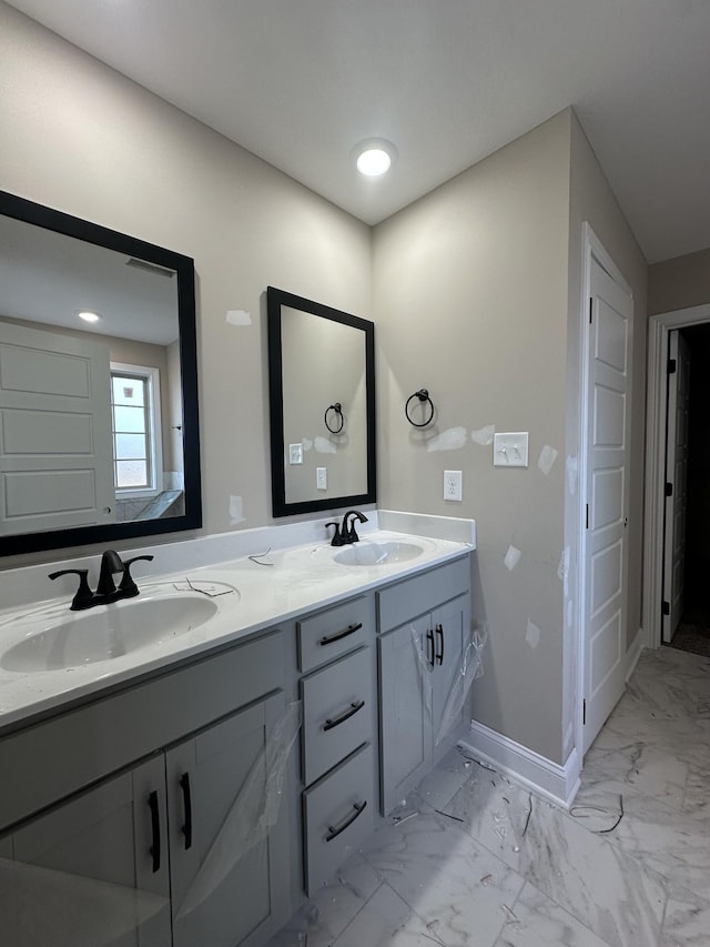 full bathroom featuring double vanity, baseboards, marble finish floor, and a sink