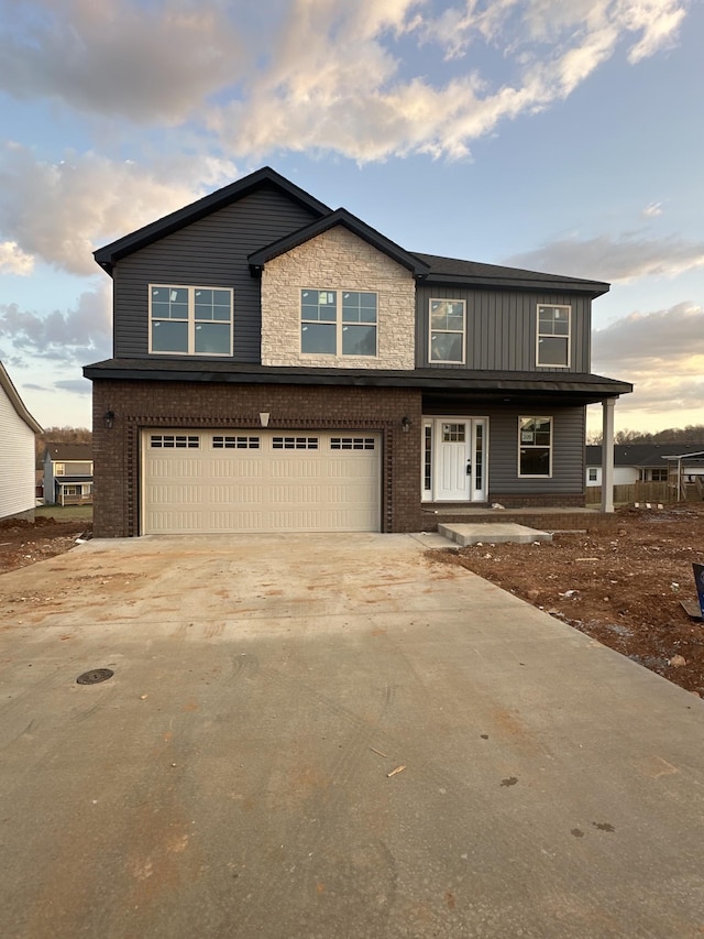 view of front facade with an attached garage, brick siding, concrete driveway, stone siding, and board and batten siding