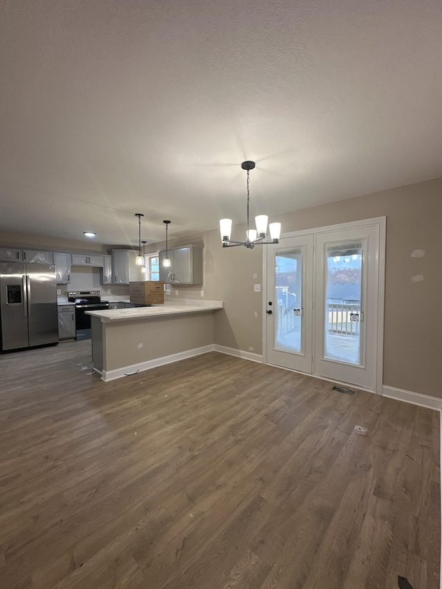 kitchen with a peninsula, stainless steel appliances, dark wood-type flooring, and an inviting chandelier