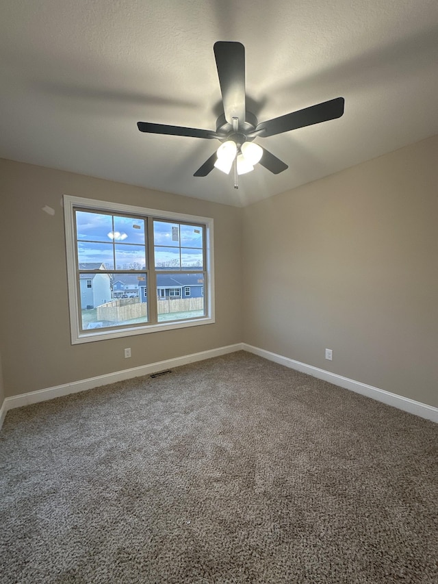 carpeted empty room featuring visible vents, ceiling fan, a textured ceiling, and baseboards