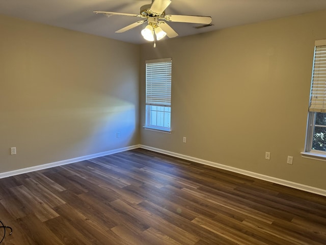 unfurnished room featuring ceiling fan, baseboards, a wealth of natural light, and dark wood finished floors