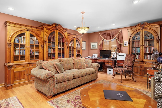 living room featuring a chandelier, light wood-type flooring, and built in desk