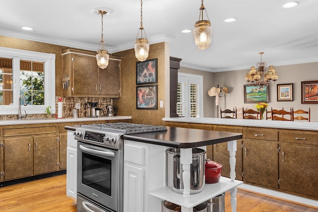 kitchen featuring hanging light fixtures, sink, high end stove, and light wood-type flooring