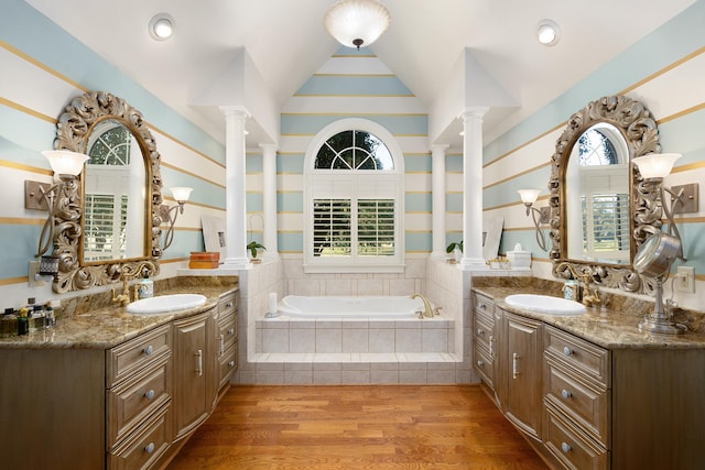 bathroom with vanity, lofted ceiling, tiled tub, and hardwood / wood-style flooring