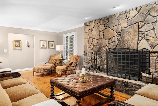 living room featuring crown molding, a stone fireplace, and wood-type flooring