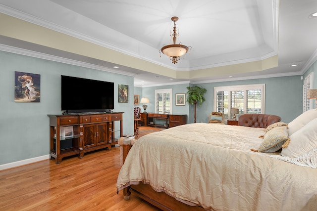 bedroom featuring light hardwood / wood-style floors, crown molding, and a raised ceiling