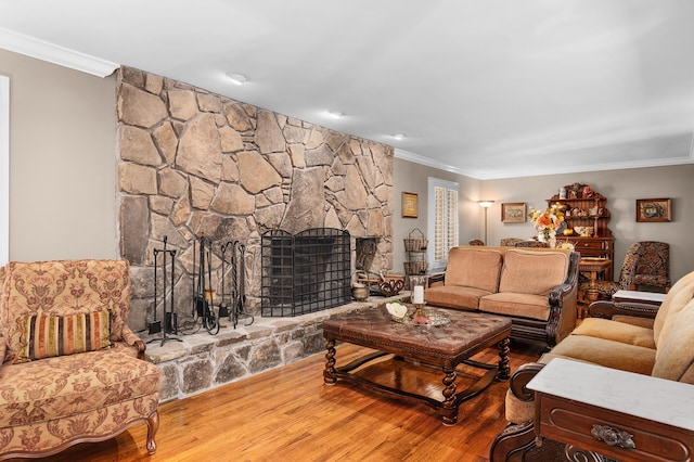 living room featuring crown molding, a stone fireplace, and hardwood / wood-style floors