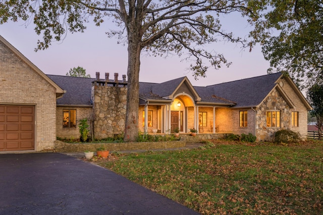 ranch-style house featuring a garage and a lawn