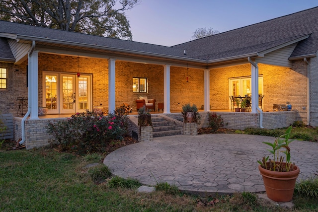 back house at dusk featuring french doors and a patio area