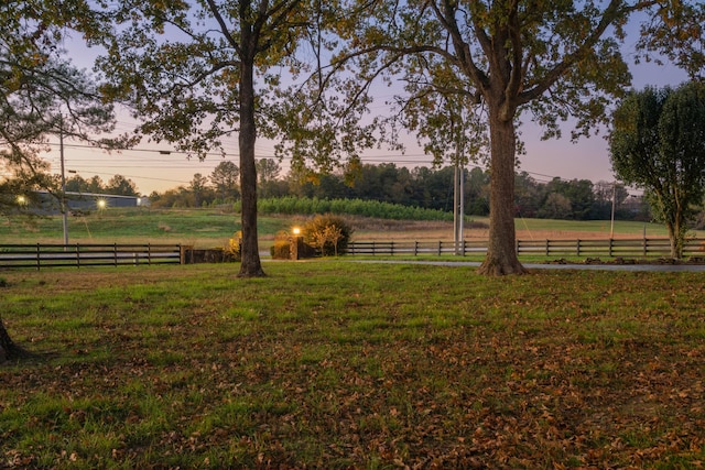 yard at dusk featuring a rural view