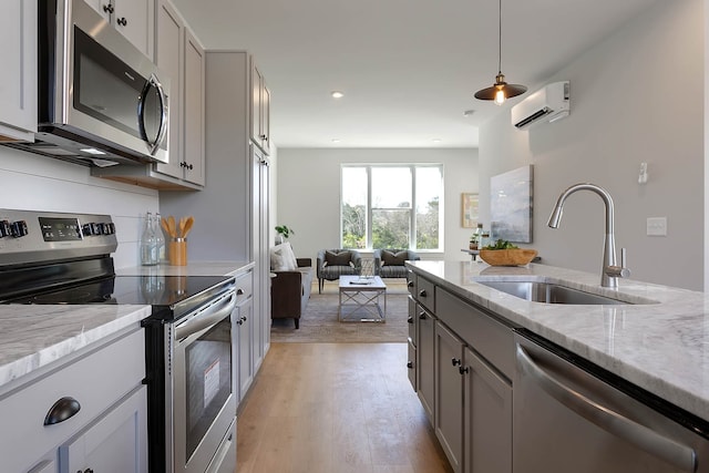 kitchen with sink, appliances with stainless steel finishes, light stone countertops, decorative light fixtures, and an AC wall unit