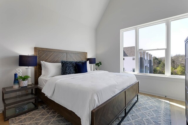 bedroom featuring light wood-type flooring and high vaulted ceiling