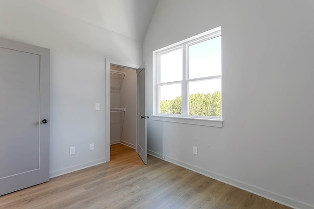 unfurnished bedroom featuring a walk in closet, a closet, and light wood-type flooring