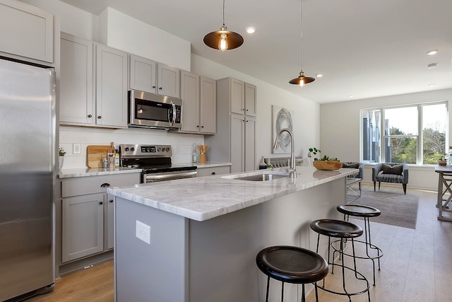 kitchen featuring stainless steel appliances, sink, hanging light fixtures, and gray cabinetry