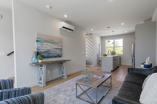 living room with sink, a wall mounted AC, and light hardwood / wood-style flooring