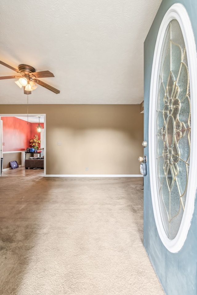 foyer entrance featuring carpet floors and ceiling fan