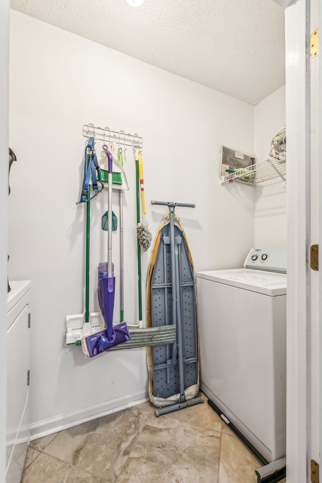 laundry room featuring washing machine and clothes dryer and a textured ceiling