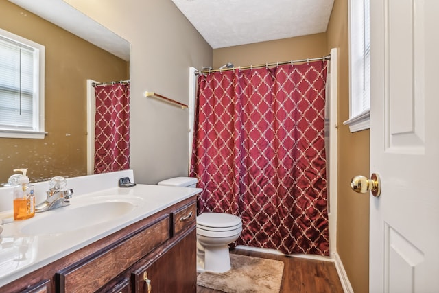 bathroom with walk in shower, toilet, a textured ceiling, vanity, and hardwood / wood-style floors