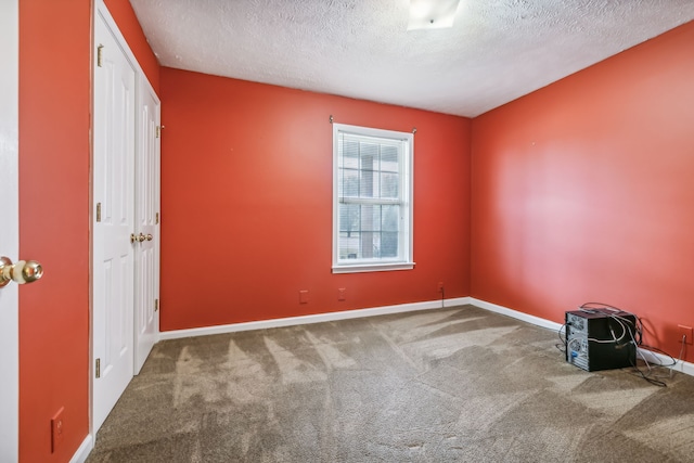 spare room featuring a textured ceiling and carpet