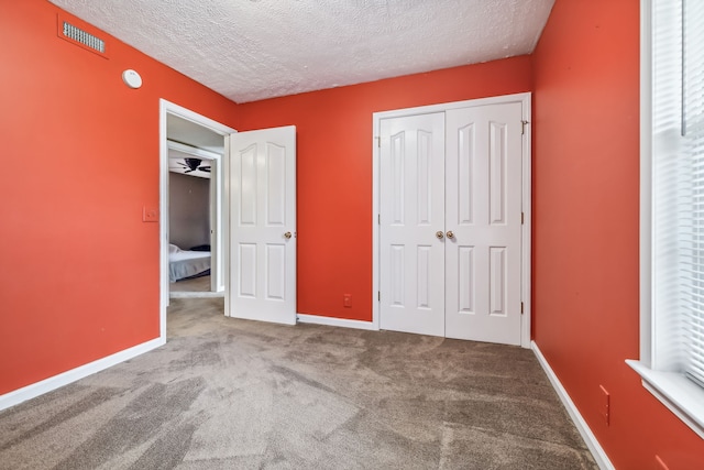 unfurnished bedroom featuring carpet floors, a textured ceiling, and a closet