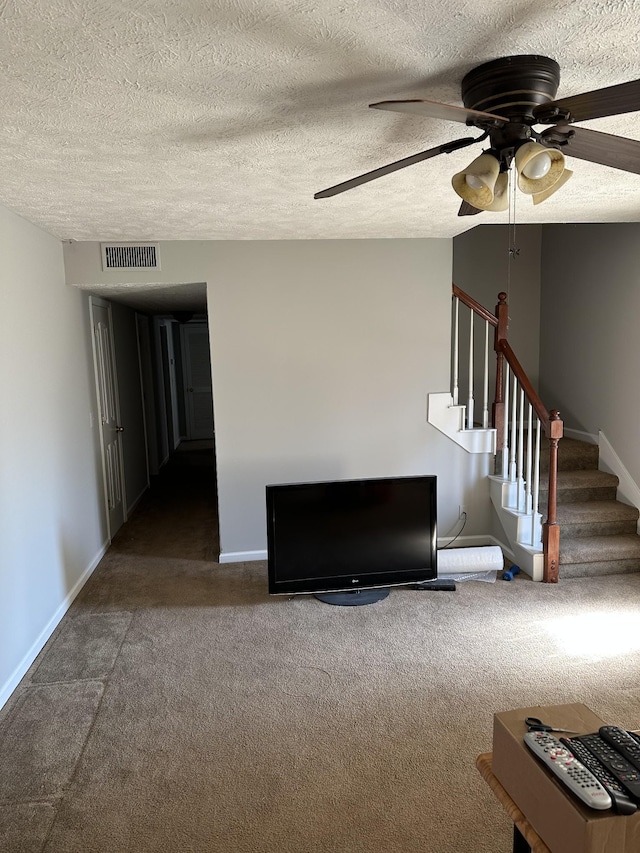 unfurnished living room with ceiling fan, a textured ceiling, and dark colored carpet