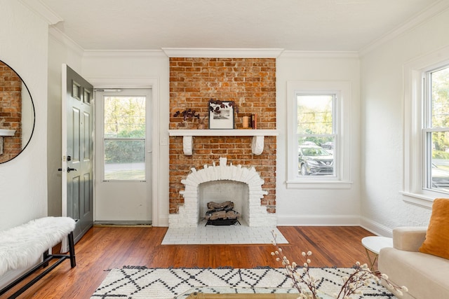 living room featuring hardwood / wood-style flooring, ornamental molding, and a brick fireplace