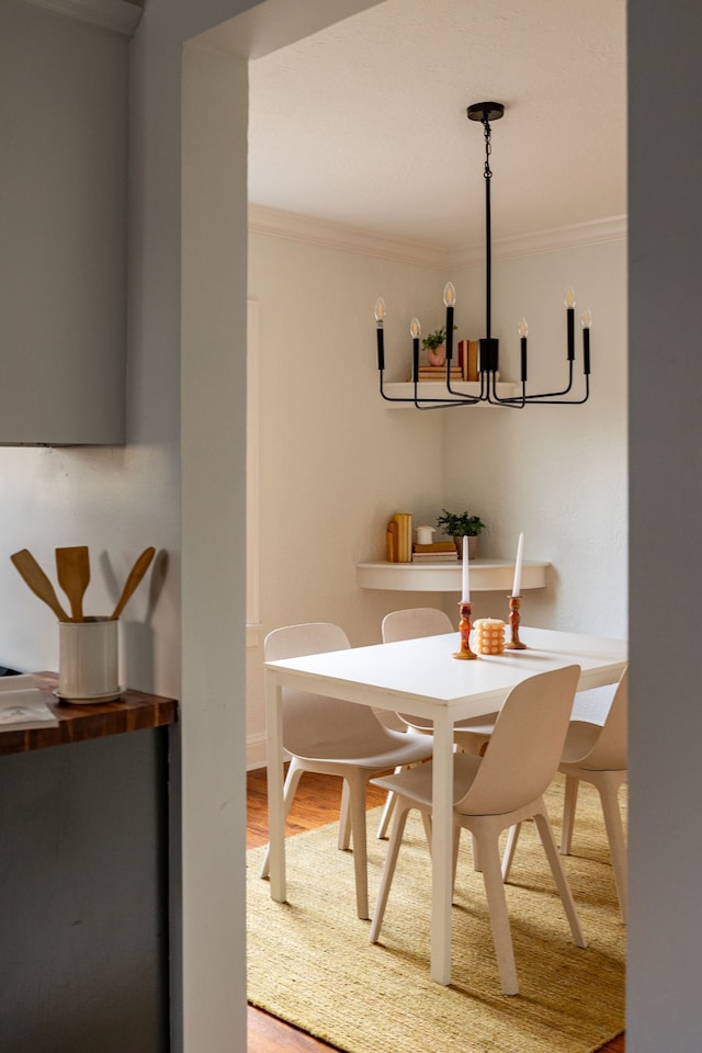 dining space with ornamental molding, hardwood / wood-style flooring, and an inviting chandelier