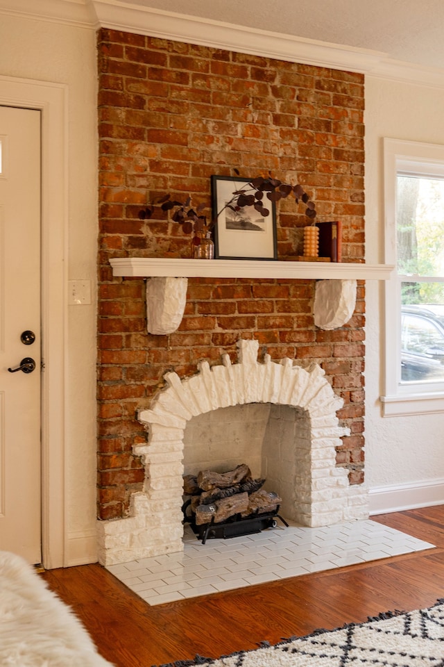 details with crown molding, wood-type flooring, and a brick fireplace