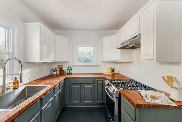 kitchen with a healthy amount of sunlight, stainless steel range with gas stovetop, butcher block counters, and white cabinets