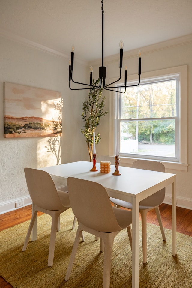 dining space featuring crown molding, wood-type flooring, and an inviting chandelier