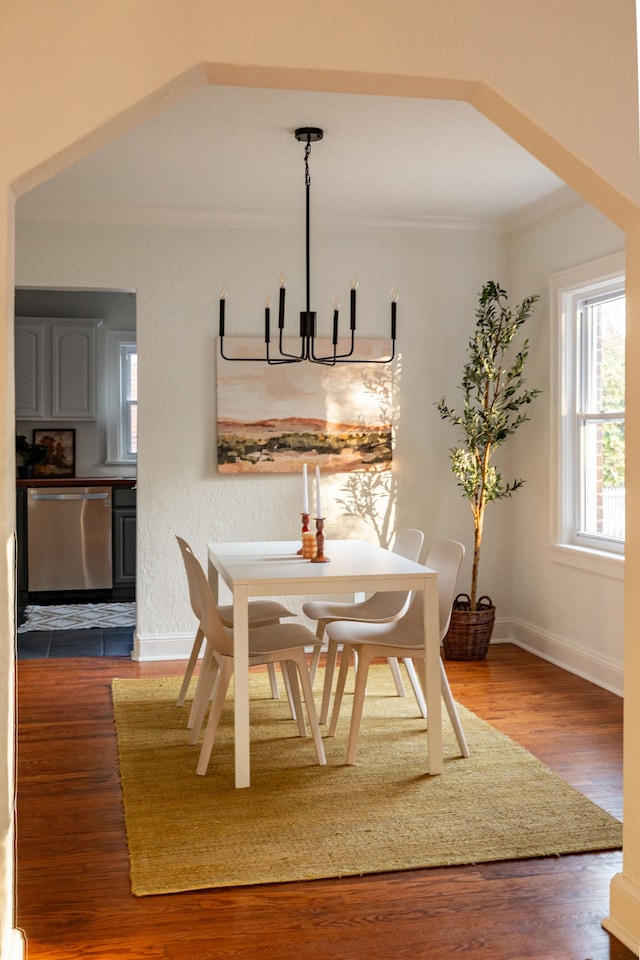 dining area featuring dark wood-type flooring, crown molding, and a chandelier