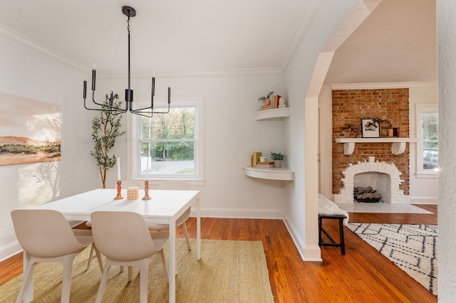 dining room with ornamental molding, hardwood / wood-style floors, a chandelier, and a fireplace