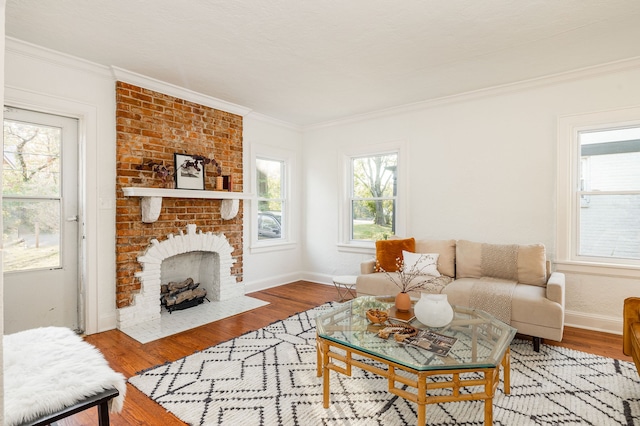 living room featuring ornamental molding, hardwood / wood-style floors, and a brick fireplace