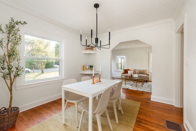 dining space featuring a healthy amount of sunlight, ornamental molding, dark hardwood / wood-style flooring, and a chandelier