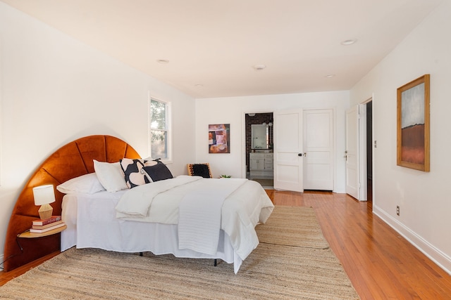 bedroom with light hardwood / wood-style floors and ensuite bath