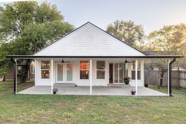 back house at dusk featuring a patio area, a yard, and ceiling fan