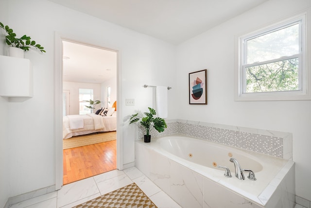 bathroom with a relaxing tiled tub and hardwood / wood-style floors