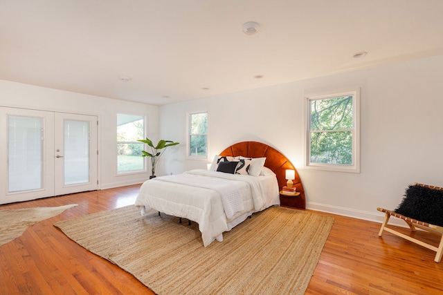 bedroom with french doors, light hardwood / wood-style flooring, and multiple windows