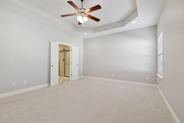 unfurnished room featuring ceiling fan, carpet flooring, and a raised ceiling