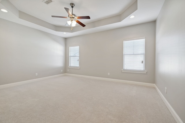 empty room featuring carpet flooring, a tray ceiling, and ceiling fan