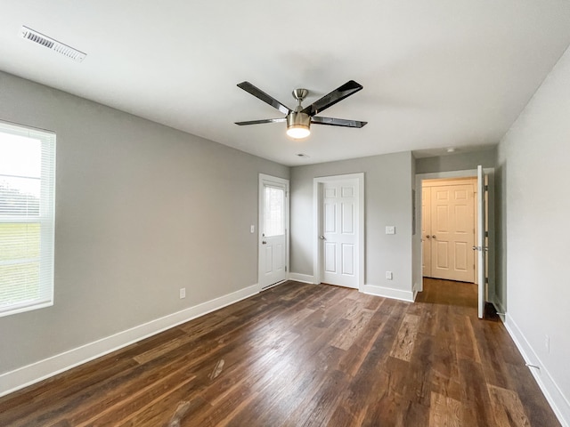 unfurnished bedroom featuring ceiling fan, multiple windows, and dark hardwood / wood-style flooring