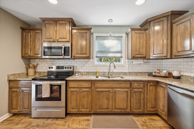 kitchen featuring sink, appliances with stainless steel finishes, light stone counters, and light hardwood / wood-style floors