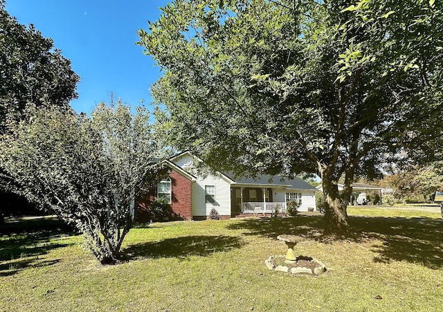 view of front of house featuring covered porch, a front lawn, and brick siding