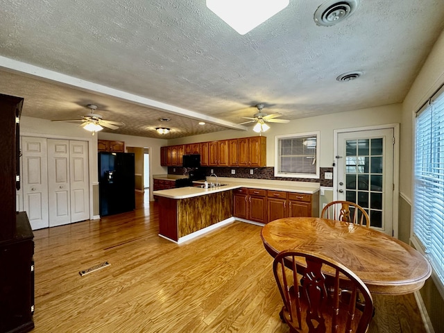 kitchen with black fridge with ice dispenser, tasteful backsplash, a textured ceiling, light wood-type flooring, and ceiling fan