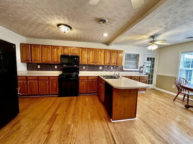 kitchen with sink, backsplash, light hardwood / wood-style flooring, and black appliances