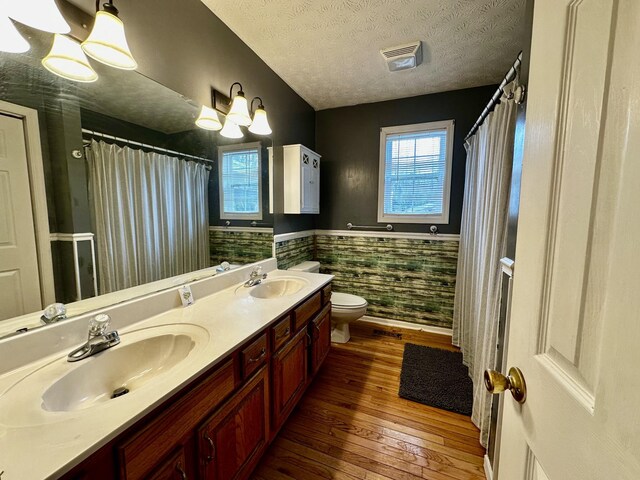 bathroom with hardwood / wood-style flooring, vanity, a textured ceiling, toilet, and a chandelier