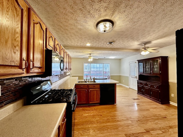 kitchen featuring sink, ceiling fan, black appliances, light hardwood / wood-style floors, and a textured ceiling