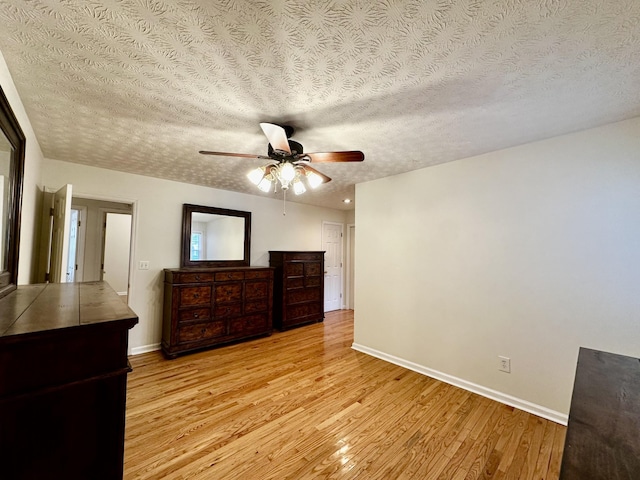 unfurnished bedroom featuring ceiling fan, a textured ceiling, and light hardwood / wood-style floors